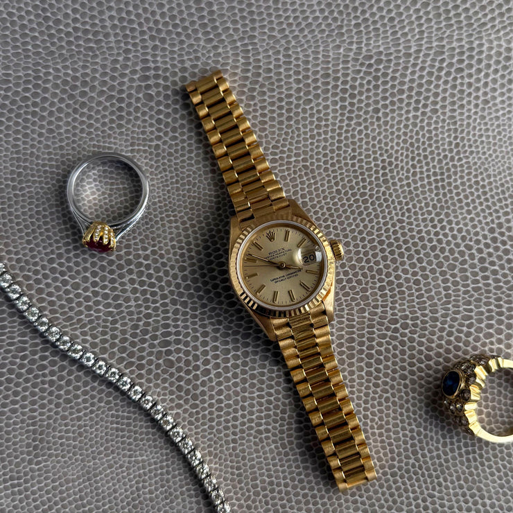 Display showing the petal and diamond setting on a ruby ring along with a rolex watch and diamond bracelet