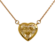 Heart-shaped yellow diamond pendant on a gold chain against a white background