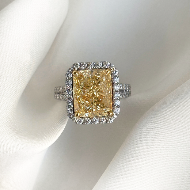 Ring with a large yellow diamond and smaller diamond halo on a white background