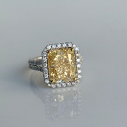 Large yellow diamond ring with a diamond halo on a gray background