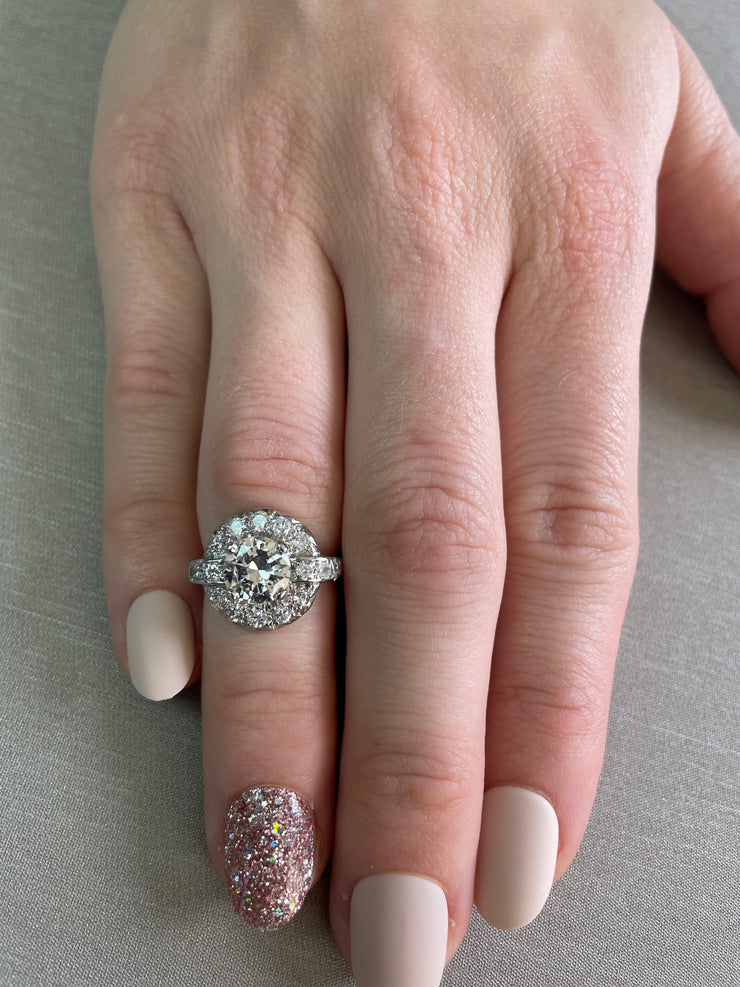 A symbol of enduring romance, this antique ring pairs a classic 1.20 ct round diamond with a halo and band set with approx. 0.60 ctw of sparkling details.