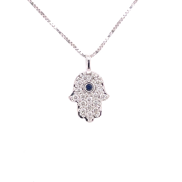 18K white gold Hamsa pendant featuring round brilliant cut diamonds and a central sapphire.