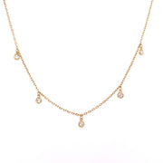A 14K yellow gold necklace featuring a series of round brilliant cut bezel-set diamonds.