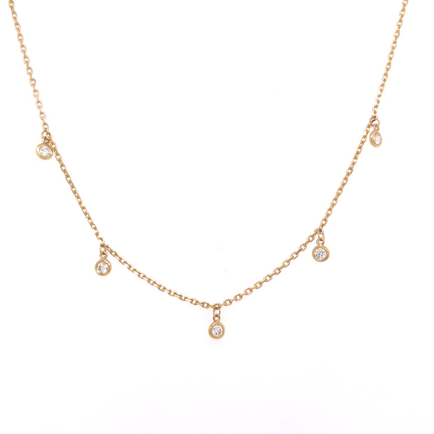 A 14K yellow gold necklace featuring a series of round brilliant cut bezel-set diamonds.