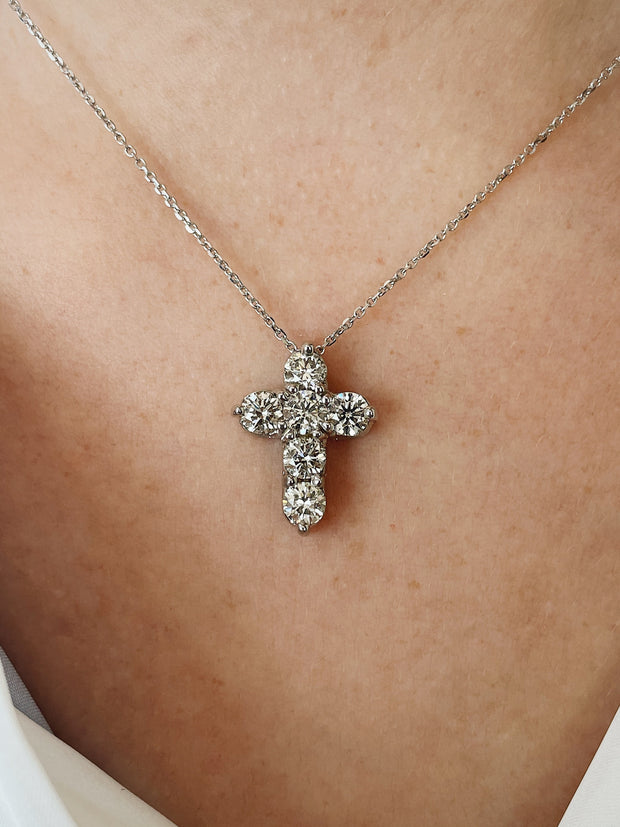 Six round brillliant diamonds set in a cross pendant sparkle on model.