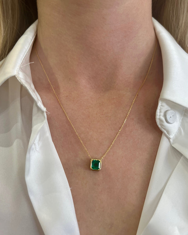 Asscher-cut emerald set in yellow gold shown on model.