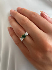 Three stone emaerald and diamond ring shown on model.
