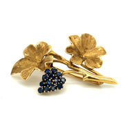 Front view of the brooch showcasing the delicate grape vine design and rich blue sapphire accents.