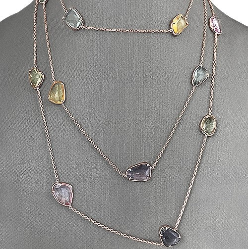 Colorful natural sapphire slice necklace layered on a gray display