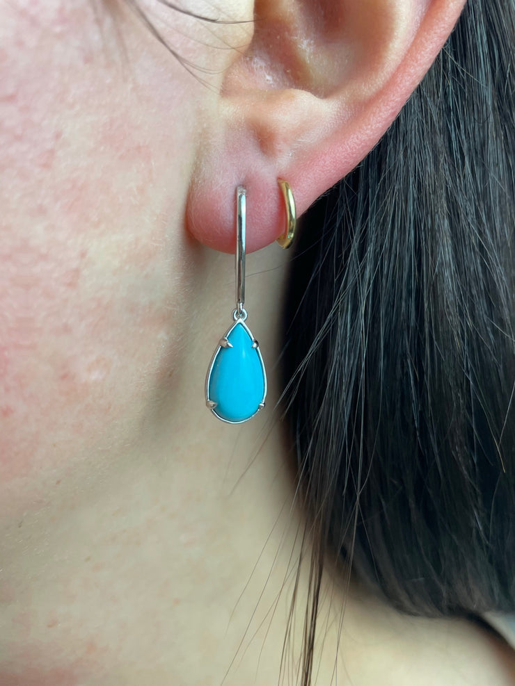 Turquoise teardrop earrings in white gold shown on model.