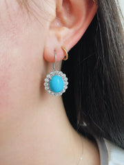 Stunning blue turquoise and diamond halo earrings shown on model.