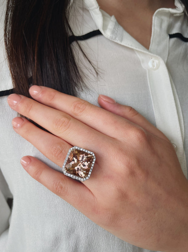 14.14 carat cushion-cut morganite secured with rose gold double prongs shown on model.