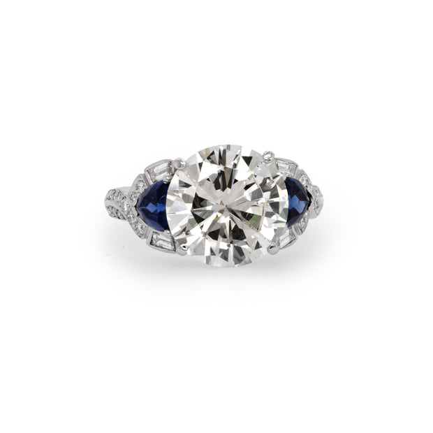  Close front view of the ring showcasing the 5.04ct round brilliant diamond between two trillion cut sapphires.