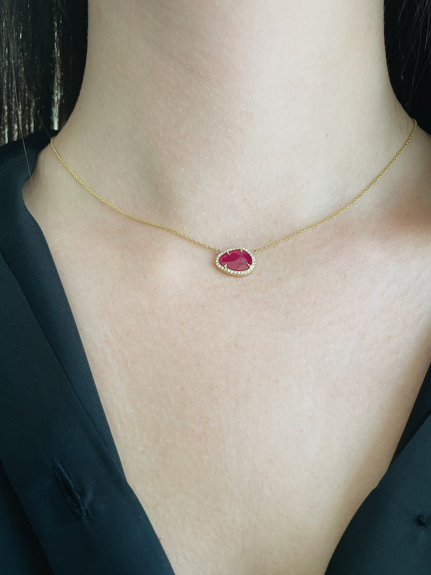 Stunning natural ruby slice with round brilliant damond halo seen on model.
