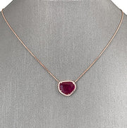 An 18 karat rose gold necklace with a central natural ruby slice and surrounding diamonds.