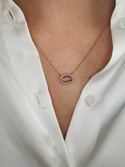 Vibrant pink sapphire and diamond halo necklace worn on model.