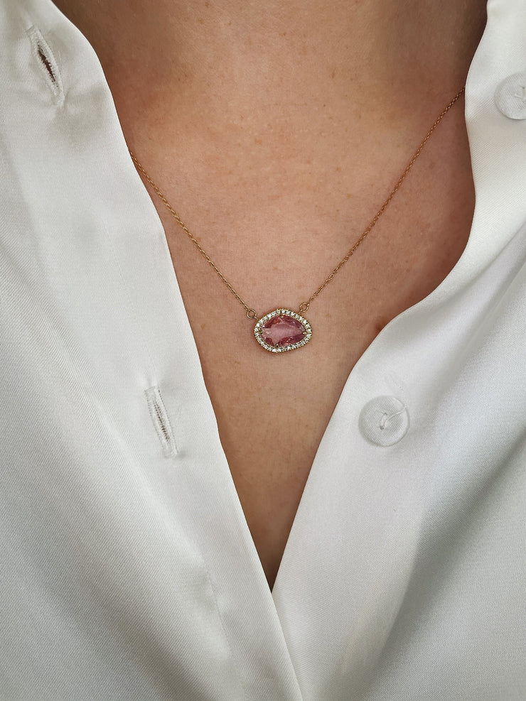Vibrant pink sapphire and diamond halo necklace worn on model.