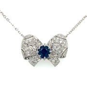 A blue sapphire center stone pendant with a diamond bow design.