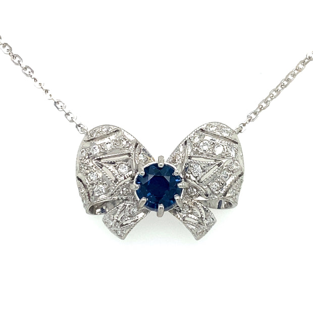 A blue sapphire center stone pendant with a diamond bow design.