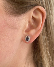 Sapphire and diamond halo stud earrings shown on model.