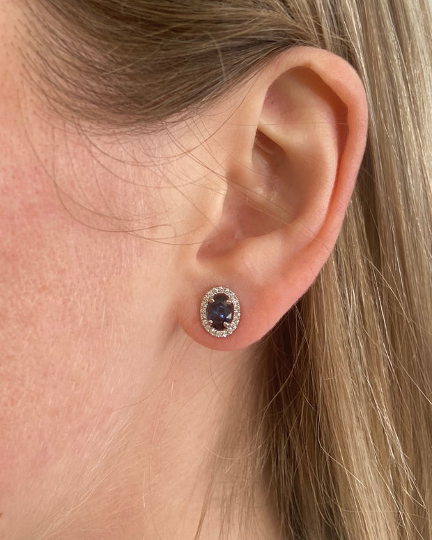 Sapphire and diamond halo stud earrings shown on model.