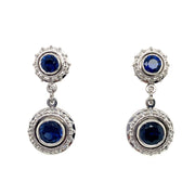 A pair of dop earrings with blue sapphire centers with diamond halos, set in platinum.