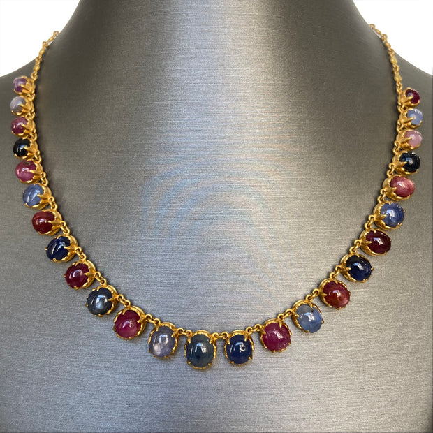 Full view of the necklace laid flat, showing alternating ruby and sapphire cabochons.