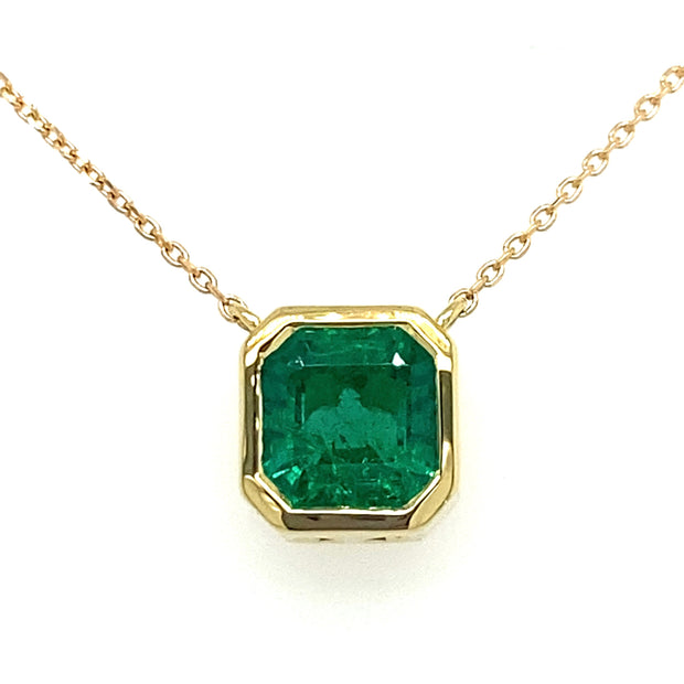 An Asscher Cut Emerald set in a 18K Yellow Gold Necklace with a white background.