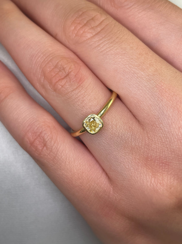 Sleek 18k yellow gold ring with vibrant fancy yellow diamond in secure bezel on a model.