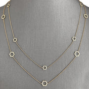 A yellow gold necklace with six floral-inspired open motifs, each accented with sparkling round brilliant diamonds.