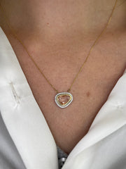 Pink sapphire and diamond halo necklace shown on model.