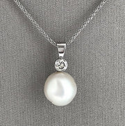 A pendant necklace featuring a round South Sea pearl and a diamond set in a white gold.