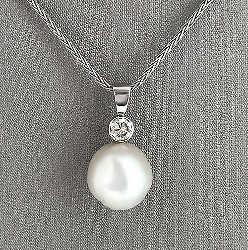 A pendant necklace featuring a round South Sea pearl and a diamond set in a white gold.