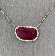 Closer detailing the faceted ruby slice with round brilliant  diamond halo.