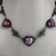 A turn of the centurynecklace featuring an 18ct rose-cut amethyst in a heart shape, surrounded by intricate vintage detailing, set in 18K yellow gold